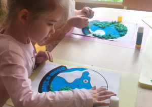 Dziewczynki kredkami pastelowymi kolorują wodę na obrazku kuli ziemskiej