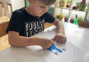 Chłopiec maluje planetę na niebiesko