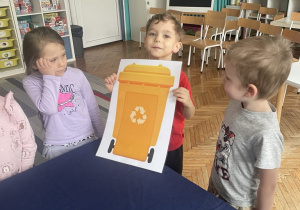 Chłopiec trzyma ilustrację kosza na śmieci w kolorze żółtym