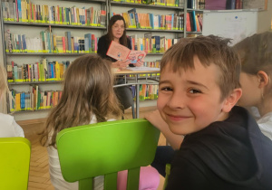 dzieci słuchaja opowiadania czytanego przez pravcownika biblioteki