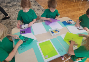 Dzieci przy stole z kopert wyjmuja puzzle