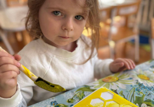 Dziewczynka maluje szablon żółtą farbą