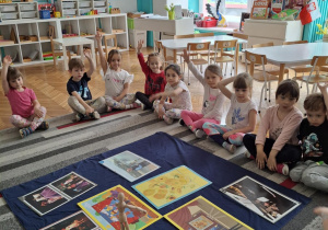 Dzieci siedzą przed planszami, które określaja sztukę: muzyka, teatr, malarstwo