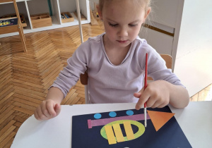 Dziewczynka maluje białe nutki obok trąbki