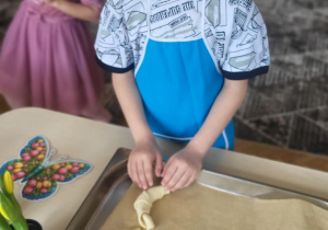 Chłopiec kladzie rogalika na blachę do pieczenia