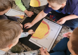 Grupa chłopców układa puzzle pizza