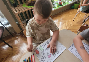 Chłopiec koloruje kolorowankę