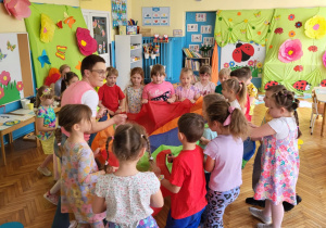 dzieci stoją po kole, trzymjąc chustę animacyjną podczas zabawy muzyczno-ruchowej