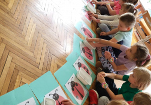 dzieci siedzą przed kartami pracy w postaci biedronek i kropek