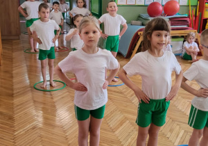 Dzieci w pozycji wyjściowej do ćwiczeń stoją w kołach