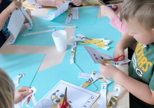Dzieci siedza przy stoliku i rozcinaka puzzle