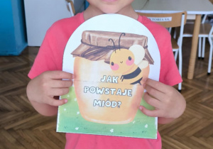 Dziewczynka z ilustracją jak powstaje miód