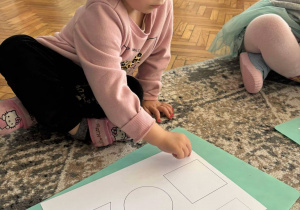 Dziewczynka z kartą pracy o figurach geometrycznych