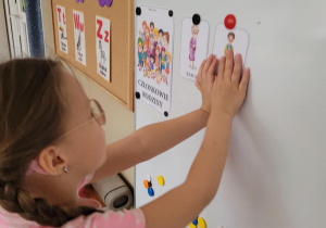 Dziewczynka przyczepia na tablice ilustrację dziadka