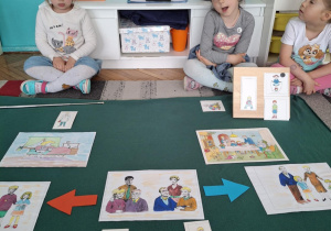 Dzieci siedza przed ilustracjami rodziny