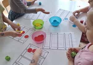 Dzieci przykaldaja czerwone kartniki na kartke