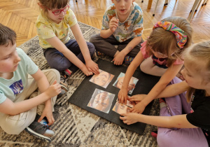 Dzieci w grupie na dywanie układają puzzle