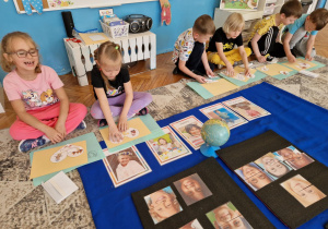 Dzieci siedzą przed ilustacjami dzieci z różnych części świata