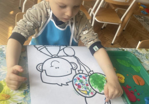 Chłopiec stepluje palcem namalowany balon