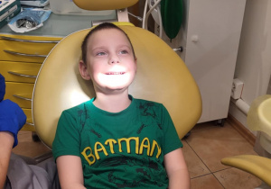 Chłopiec siedzi na fotelu dentystycznym