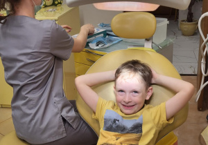 Chłopiec czeka na fotelu dentystycznym na sprawdzenie stanu uzębienia