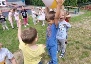 Dzieci podają sobie piłkę w kole