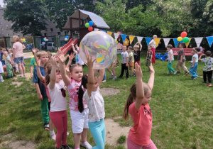 Dziewczynki idąc w kole podają sobie balon
