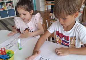 Dzieci przy stoliku przyklejają puzzle