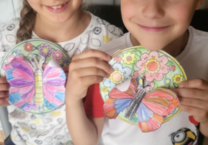 Chłopiec z dziewczynka prezentują prace plastyczną motyl na łące