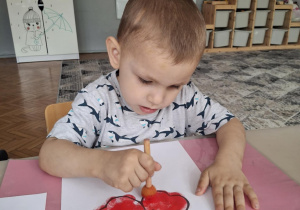 Chłopiec na czerwono stempluje kwiatka
