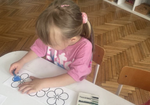 Dziewczynka maluje na niebiesko kwiatka