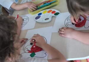 Dzieci przy stoliku malują farbami