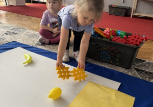Dziewczynka kladzie dwa żółte klocki