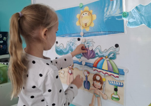 Dziewczynka przyczepia do tablicy muszelki