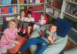 Dzieci oglądają ksiązki leżąc na poduchach