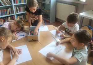 Dzieci przy stoliku wykonują pracę plastyczną