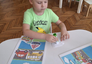 Chłopiec smaruje klejem samolot