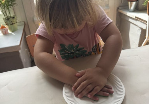 Dziewczynka odbija swoją dłoń na talerzyku