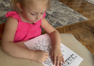 Dziewczynka koloruje ilustrację słoneczka