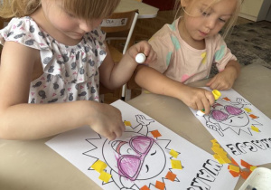 Dziewczynki przyklejają bibułę na promienie słońca