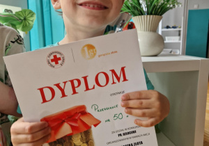 Chłopiec z dyplomem za udział w akcji charytatywnej "Gorączka złota"