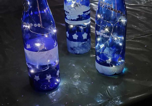 podświetlone butelki w zimowej scenerii stoją na stole