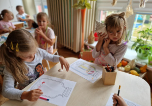Dziewczynka przy stoliku słucha odgłosów dobiegających z wnętrza muszli