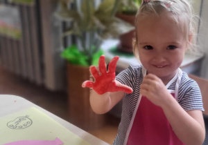 Dziewczynka ma pomalowaną na czerwono dłoń