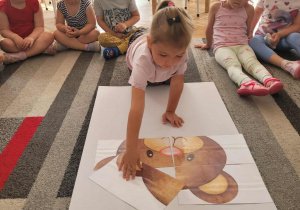 Dziewczynka ukLada głowę misia z puzzli