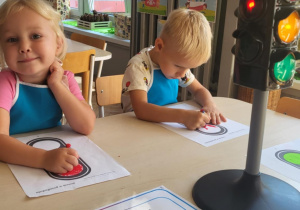 Dzieci przy stoliku kolorują czerwone światło na sygnalizatorze