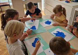 Dzieci siedzą przy stoliku ze słomkami
