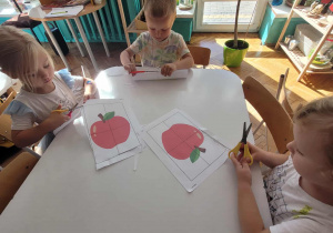 Dzieci siedzą przy stoliku z nożyczkami