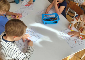 Dzieci siedzą przy stole i kolorują obrazek