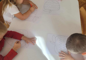 Dzieci na karcie pracy kreślą znaki literopodobne